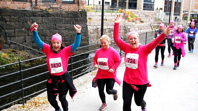 Participants in the Pink Ribbon race run with their arms in the air.