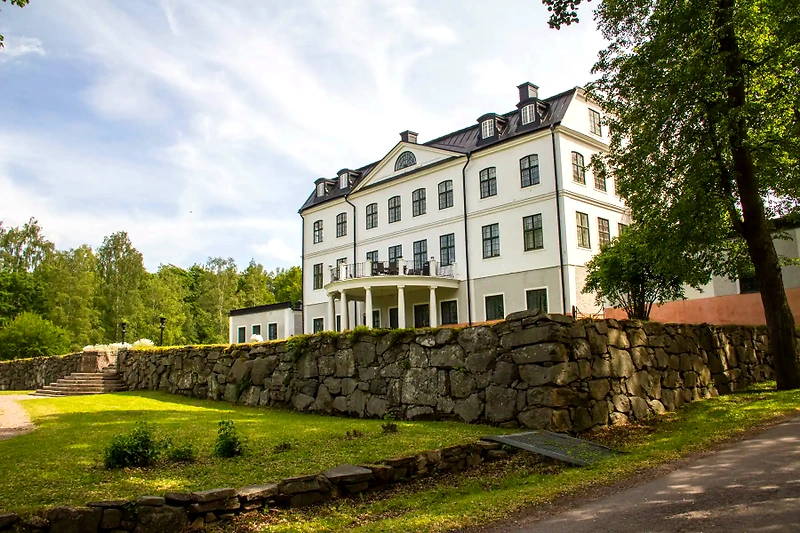Saga at Kjekstad bruk. Building with stone wall and green area.