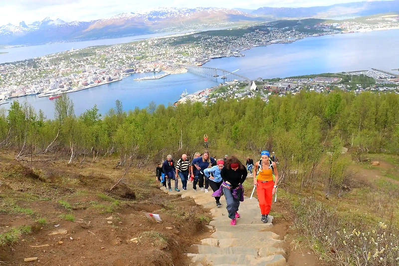 Runners on their way up the Sherpa Steps in Tromsø, with a view of the city and mountains.