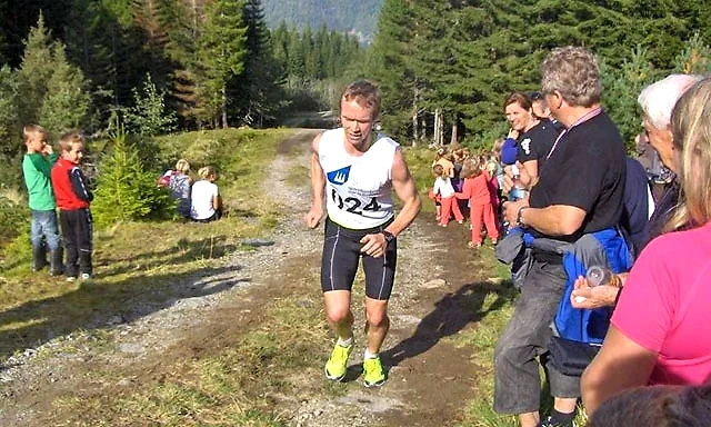 Runner in a cross-country race, with spectators along the course.