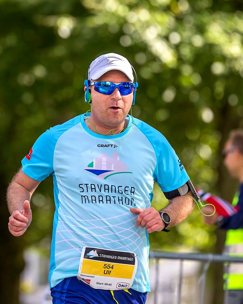 Runner in the Stavanger Marathon with bib number 554, light blue shirt, and sunglasses.