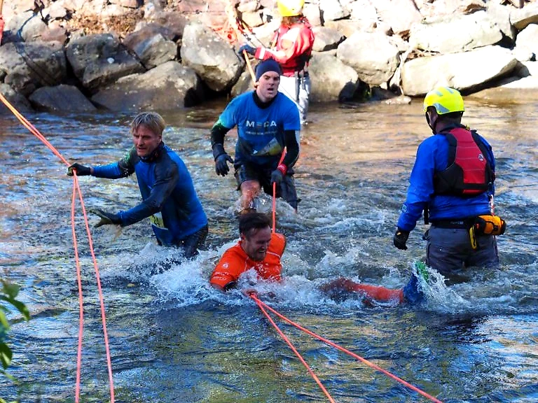 Participants in obstacle races cross water using ropes.