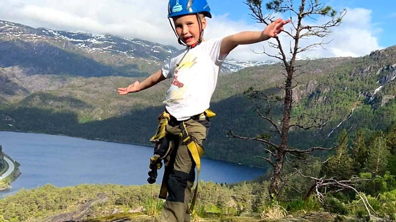 Children in helmets and harnesses on a mountain trip in Norway, likely participating in trail running.