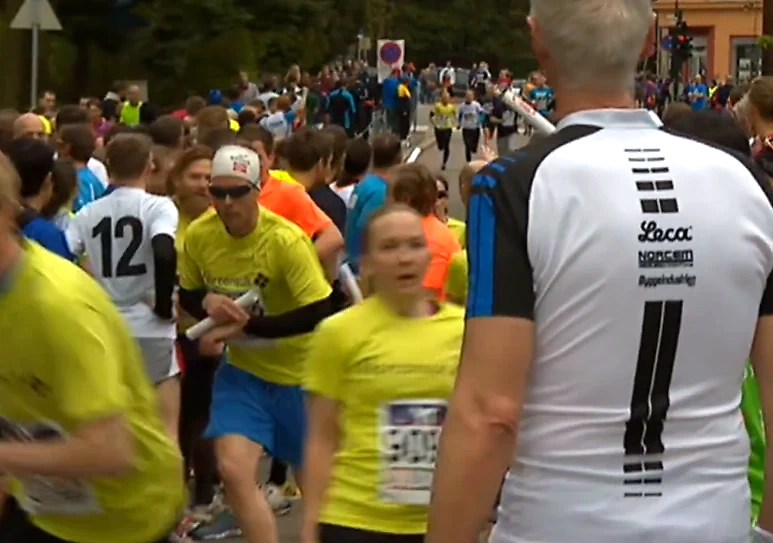 Runners in the Trondheim Forest Marathon, showcasing sponsors and the start of the race.