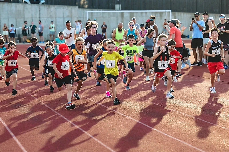 Children's race on the track. Several runners at the start.