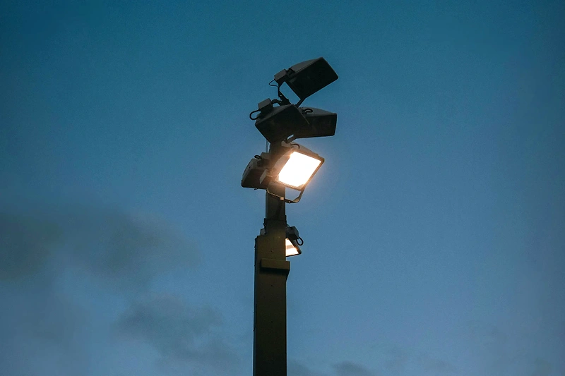 Light pole with stadium lights against a blue sky, fitting for the Twilight 5000 race.