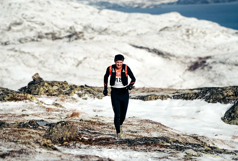 Runner in mountainous terrain with snow.