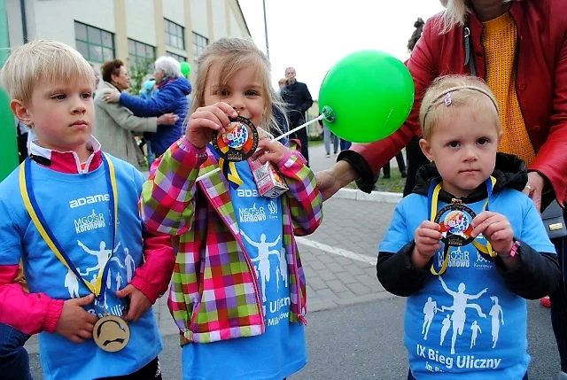 Dzieci z medalami na biegu ulicznym, sugerujące radość i udział w wydarzeniu sportowym.