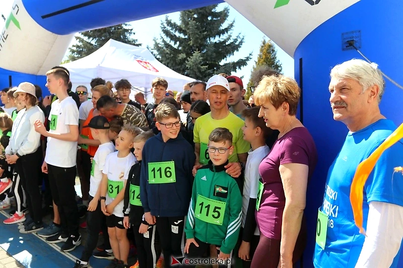 Grupa ludzi na starcie biegu, z numerami startowymi.
