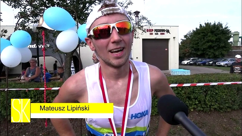 Biegacz z medalem po wyścigu, udzielający wywiadu.