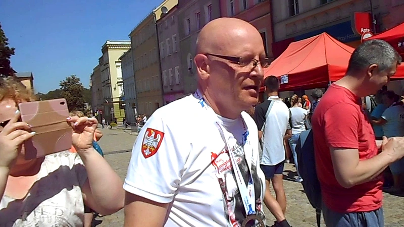 Ludzie na ulicy, prawdopodobnie biegacze, podczas imprezy sportowej.