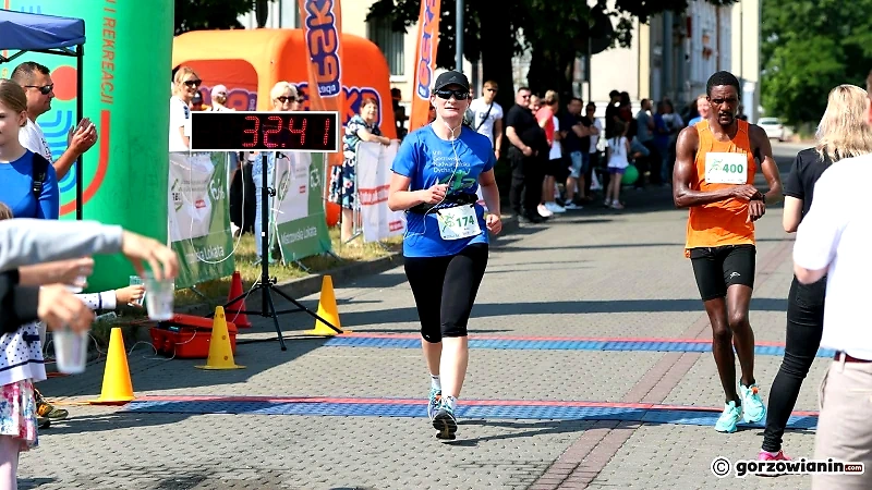 Biegacze podczas wyścigu, z widocznym czasem i kibicami.