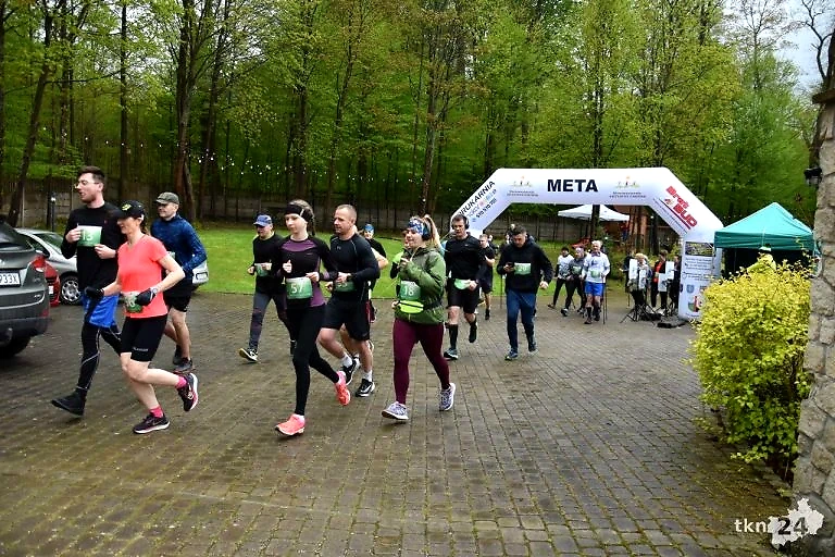 Biegacze na starcie biegu. Widoczna meta i zielone otoczenie.