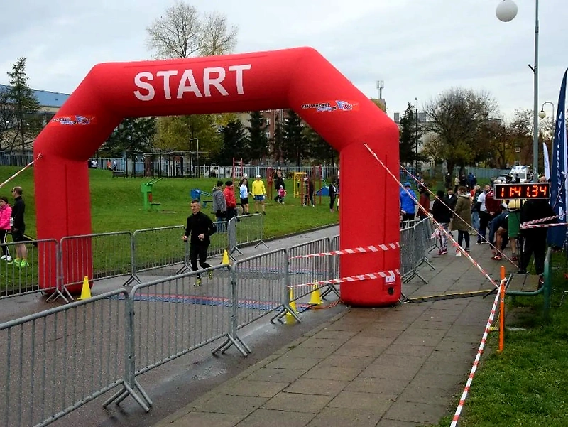 Runners at the start of the race, a red arch with the word START.