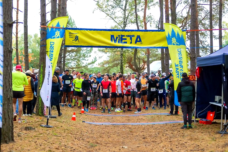 Biegacze na starcie 5 Radzymińskiego Trail, meta w tle.