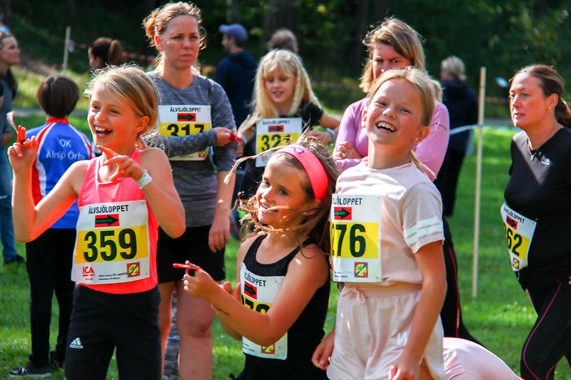 Löpare i Älvsjöloppet, med nummerlappar och leende ansikten.