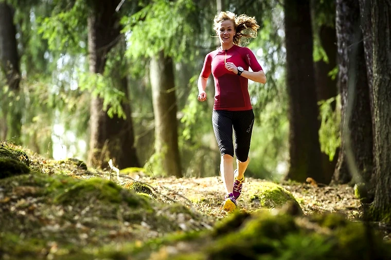 Woman running on a trail in the woods.