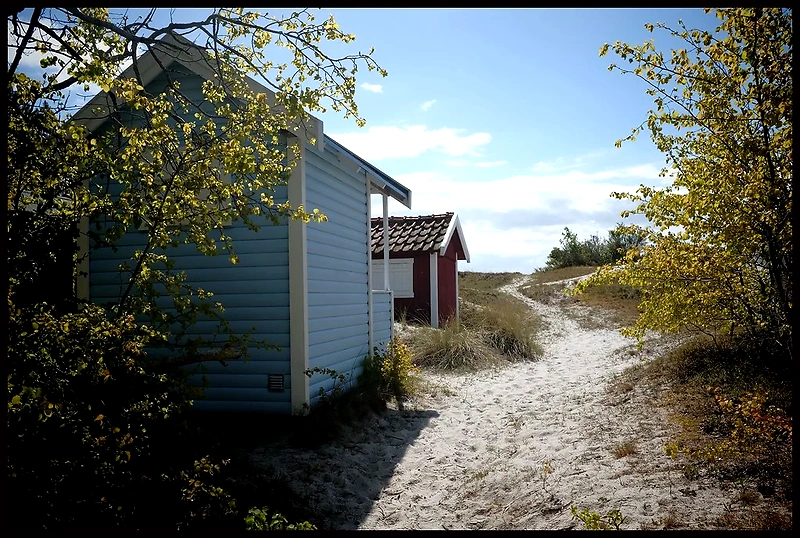 Strandväg med små stugor, soligt och vackert.