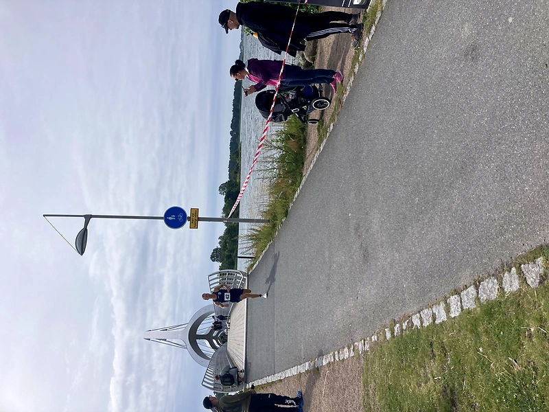 En löpare på en väg med åskådare och en vacker bro i bakgrunden.