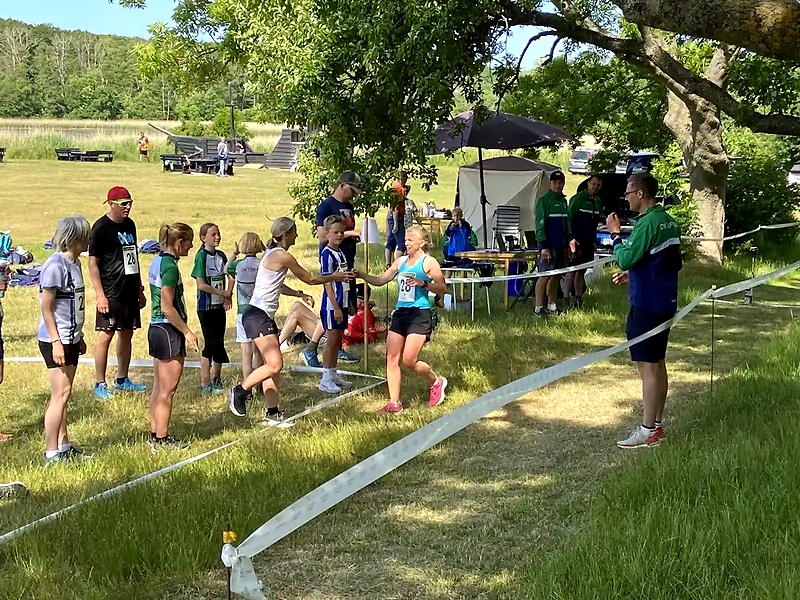 Löftanloppet stafettlag i växling. Löpare överlämnar stafettpinnen.