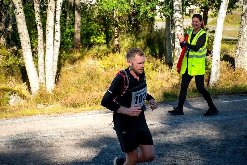 Löpare i terränglopp, en kvinna i väst applåderar.
