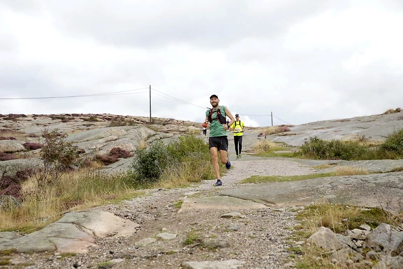 Löpare på stenig stig under molnig himmel, perfekt för trail running.
