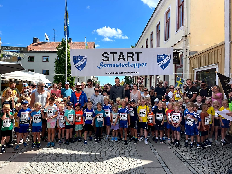 Children gather at the start of the Holiday Race with a large banner.