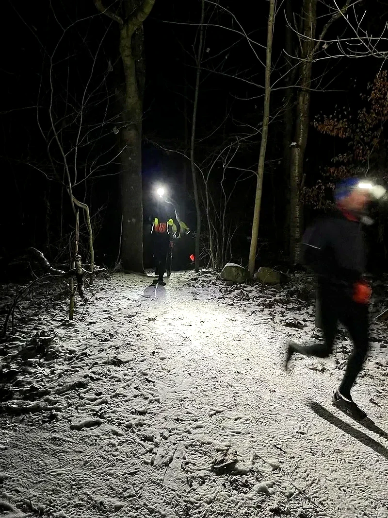 Löpare på snöig stig i mörkret, med pannlampor.