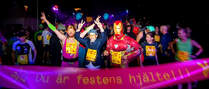 Runners in costumes at the Stadium Night Run, with a festive atmosphere.