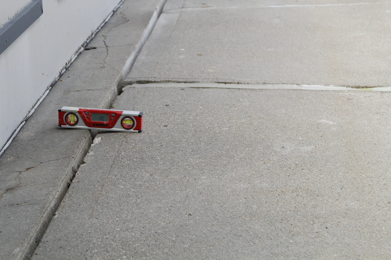 Contractor evaluating an uneven residential concrete driveway in Toledo with a laser level Contractor evaluating an uneven residential concrete driveway in Toledo with a laser level