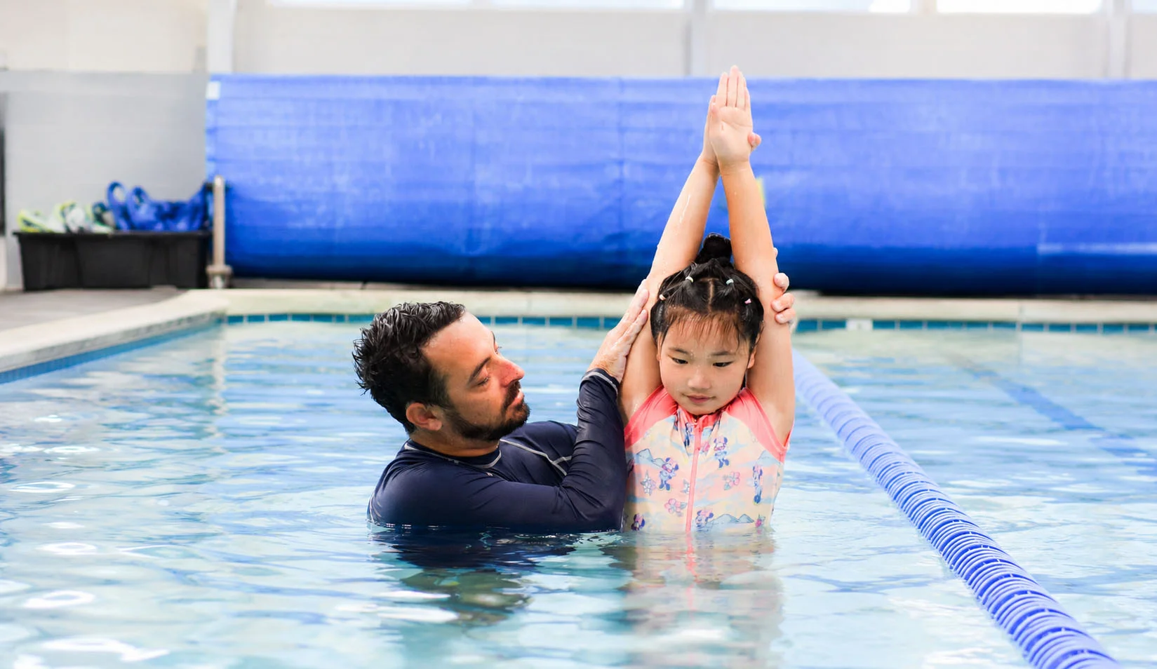 A dedicated swim instructor guiding a young swimmer on their back float A dedicated swim instructor guiding a young swimmer on their back float
