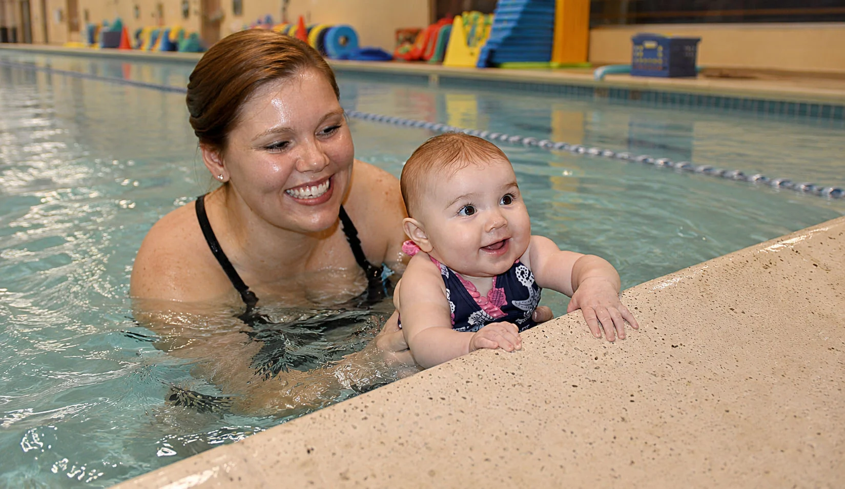 Caregiver gently pouring water over baby shoulders during bath conditioning Caregiver gently pouring water over baby shoulders during bath conditioning
