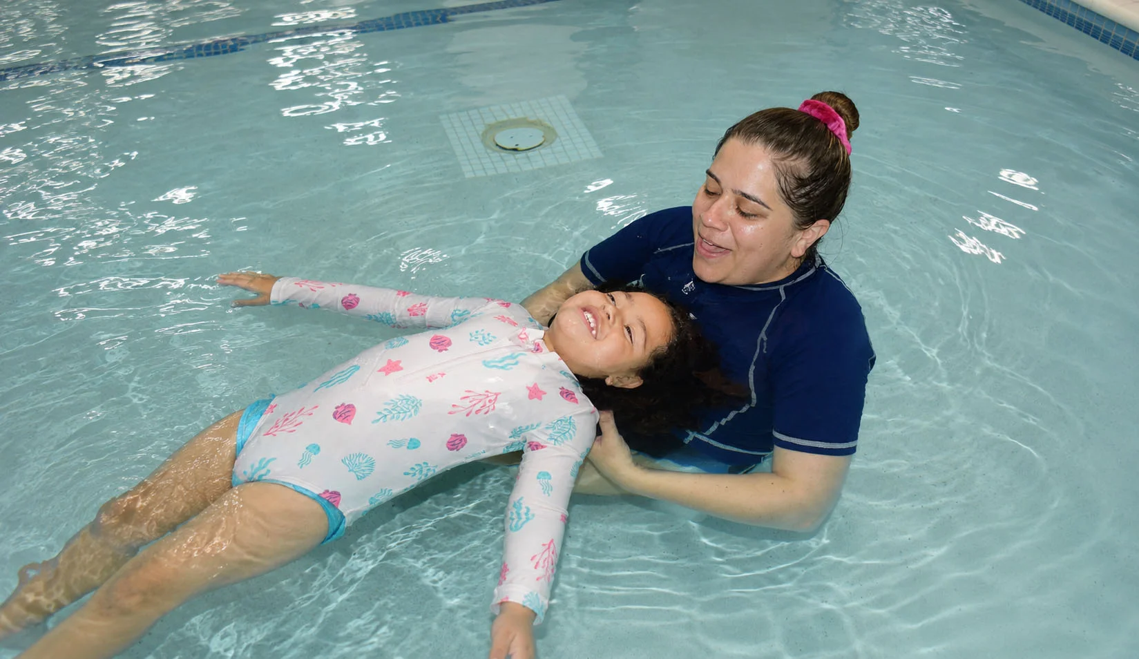 Toddler practicing water comfort and back floating skills with an instructor Toddler practicing water comfort and back floating skills with an instructor