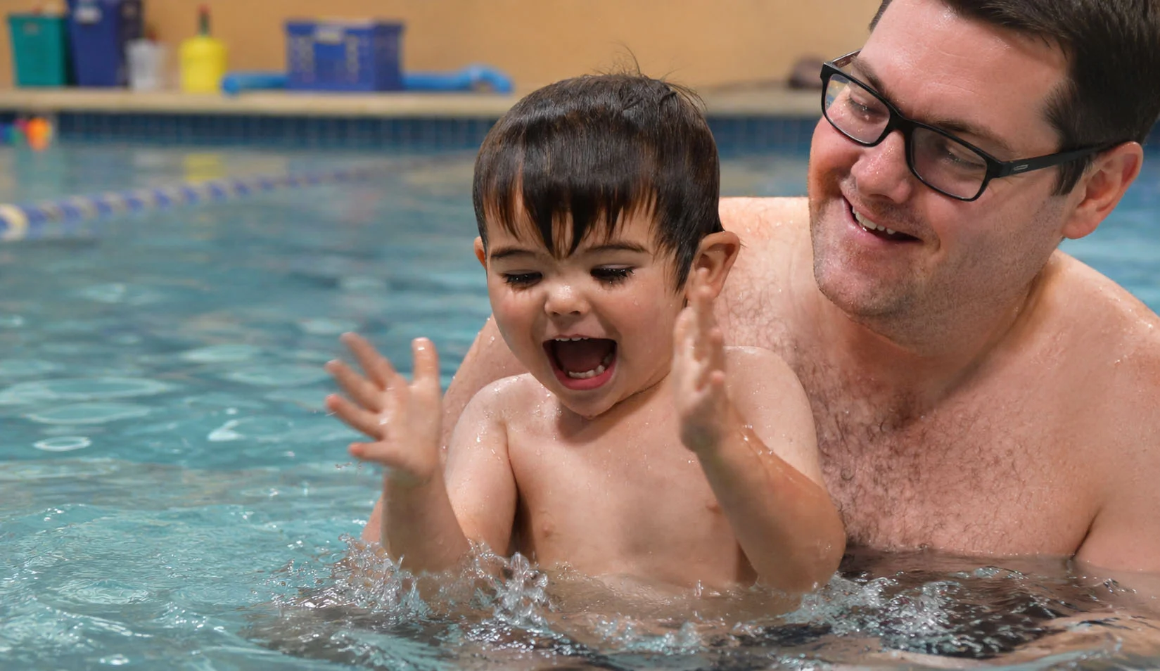 toddler splashing with a parent in a warm indoor pool toddler splashing with a parent in a warm indoor pool