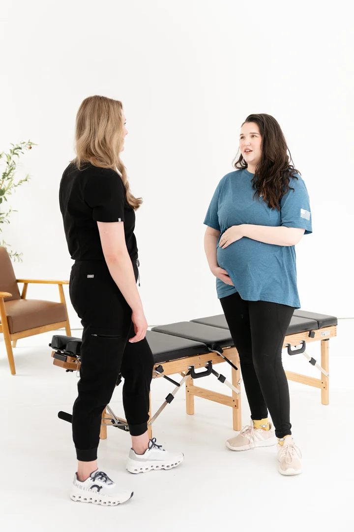 chiropractor gently checking spinal alignment for a pregnant patient