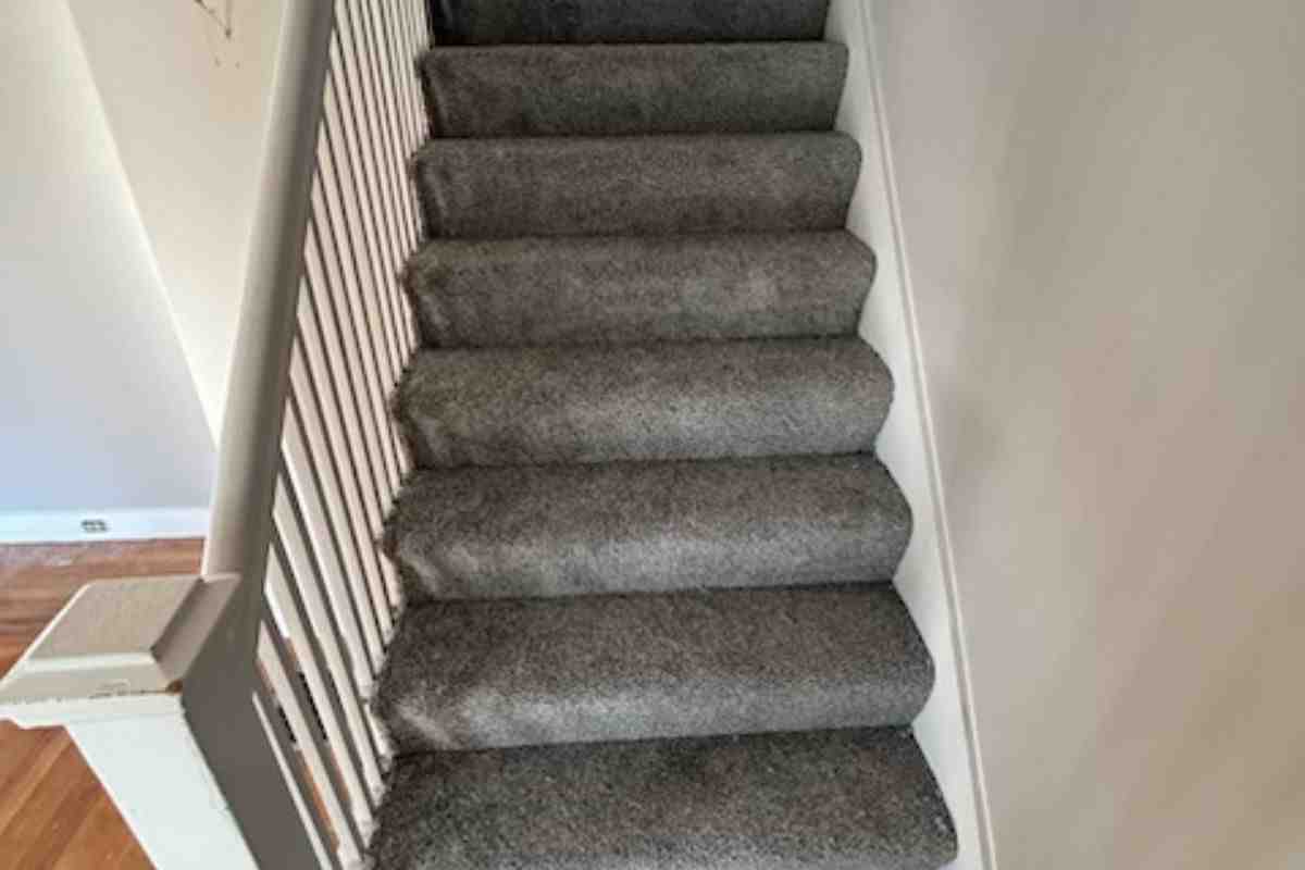 Professional installer working on stairs with carpet installation tools - carpet changing cost