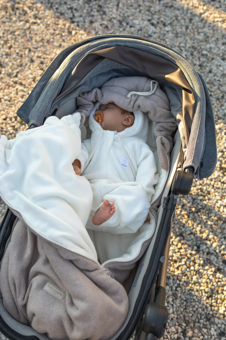 Parent securely wrapping baby in cold weather swaddle