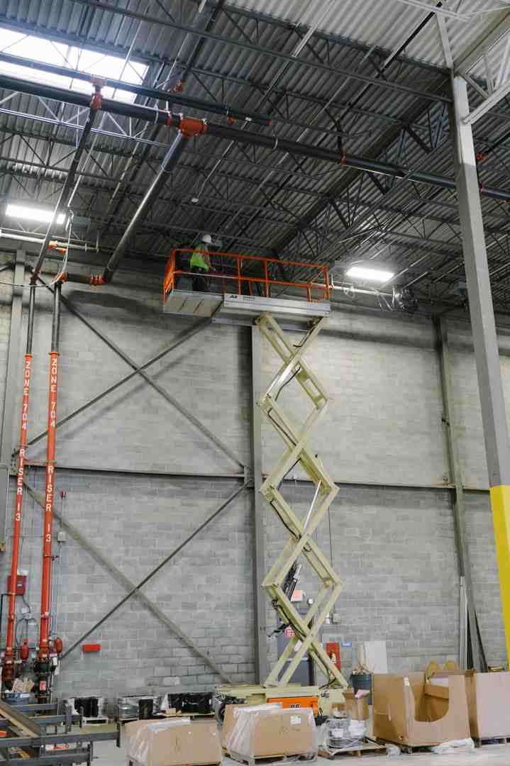 commercial electricians installing high-bay fan with lift