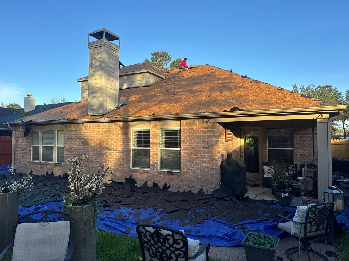 Professional roofer installing a temporary tarp on a damaged asphalt shingle roof Professional roofer installing a temporary tarp on a damaged asphalt shingle roof