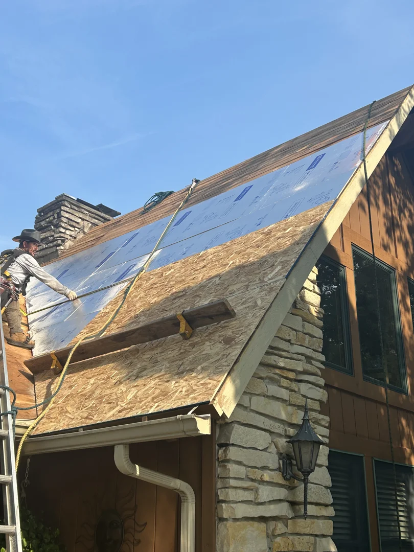 roofing contractor installing self-adhering leak barrier underlayment over roof deck slot roofing contractor installing self-adhering leak barrier underlayment over roof deck slot