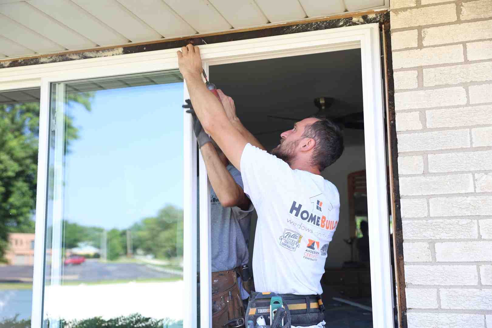 A homeowner carefully lifting a storm door slab into the frame