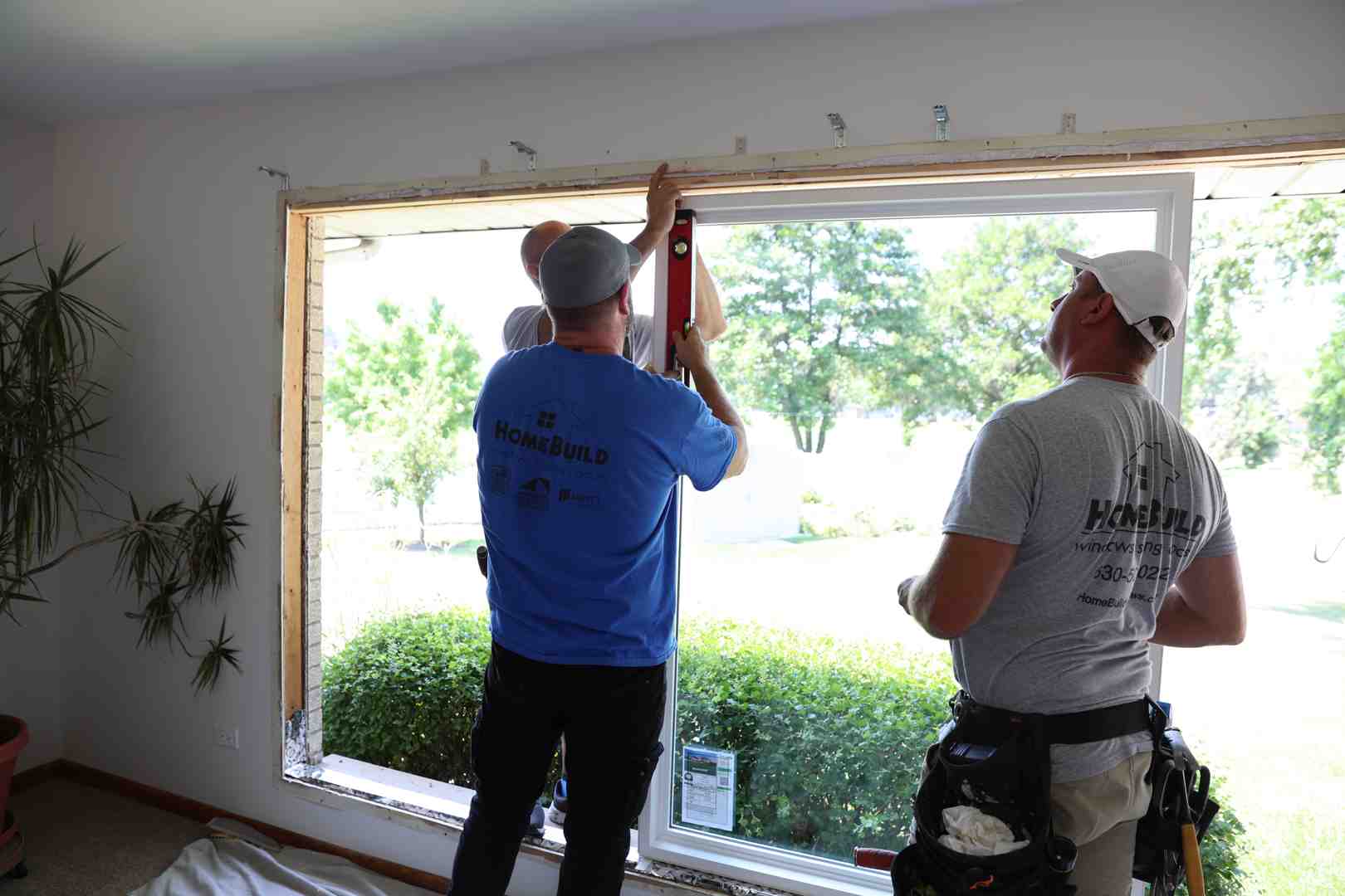 Professional installers carefully fitting a new bay window into a residential home exterior