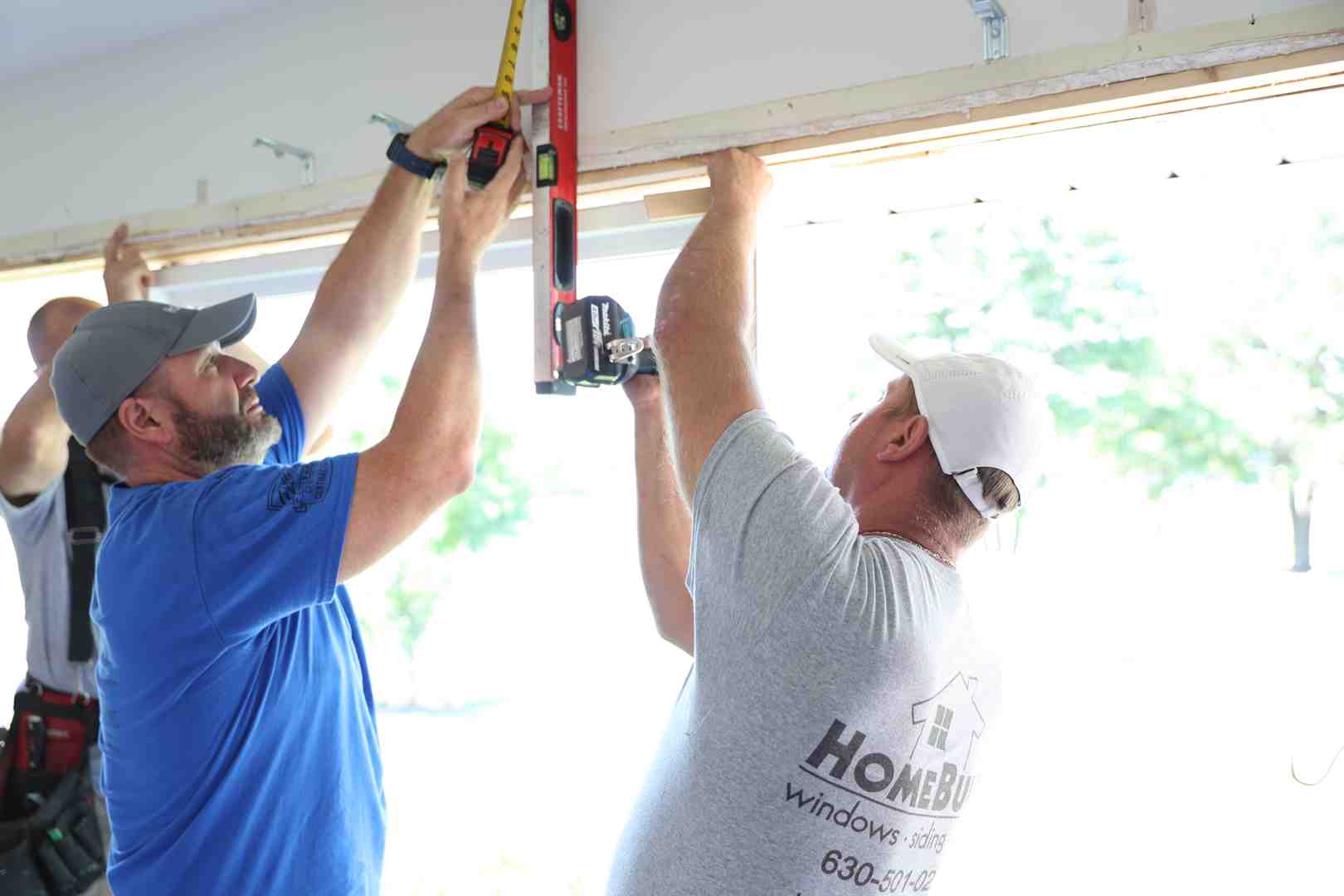 Worker placing and leveling replacement window in vinyl opening