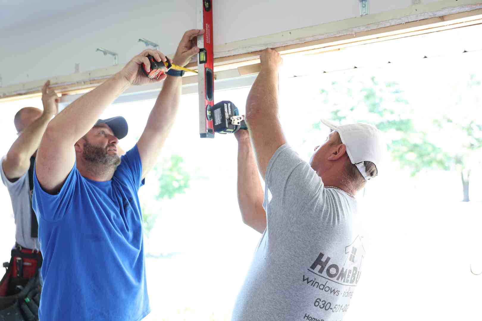 contractor measuring siding panels during installation