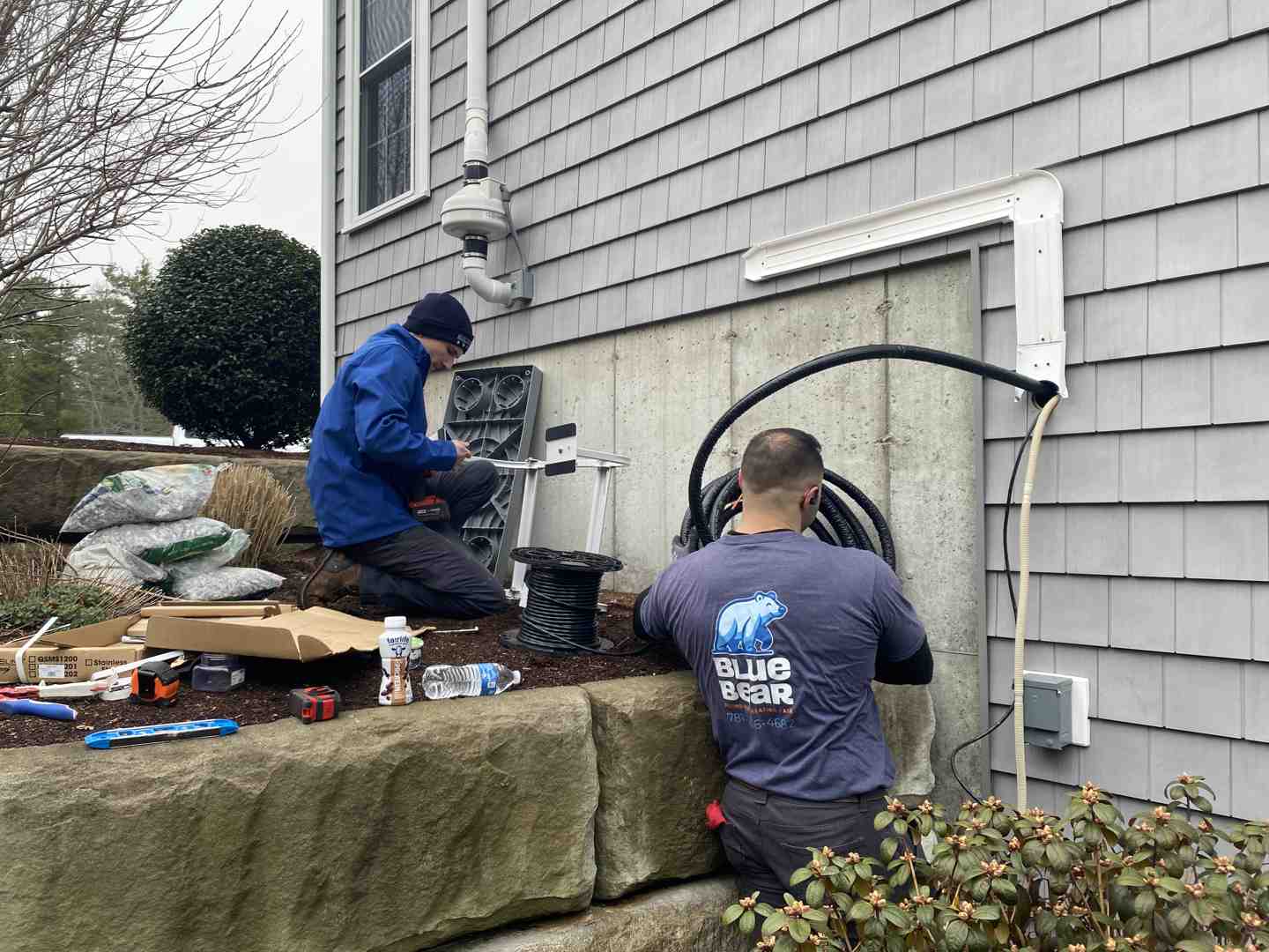 technician installing a high-efficiency heat pump system outside a suburban home technician installing a high-efficiency heat pump system outside a suburban home