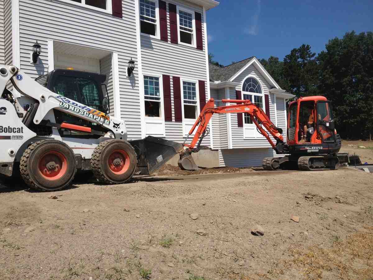 A landscaper meticulously grading the soil and adding fresh loam to prepare for a new lawn installation. - lawn installation salem nh