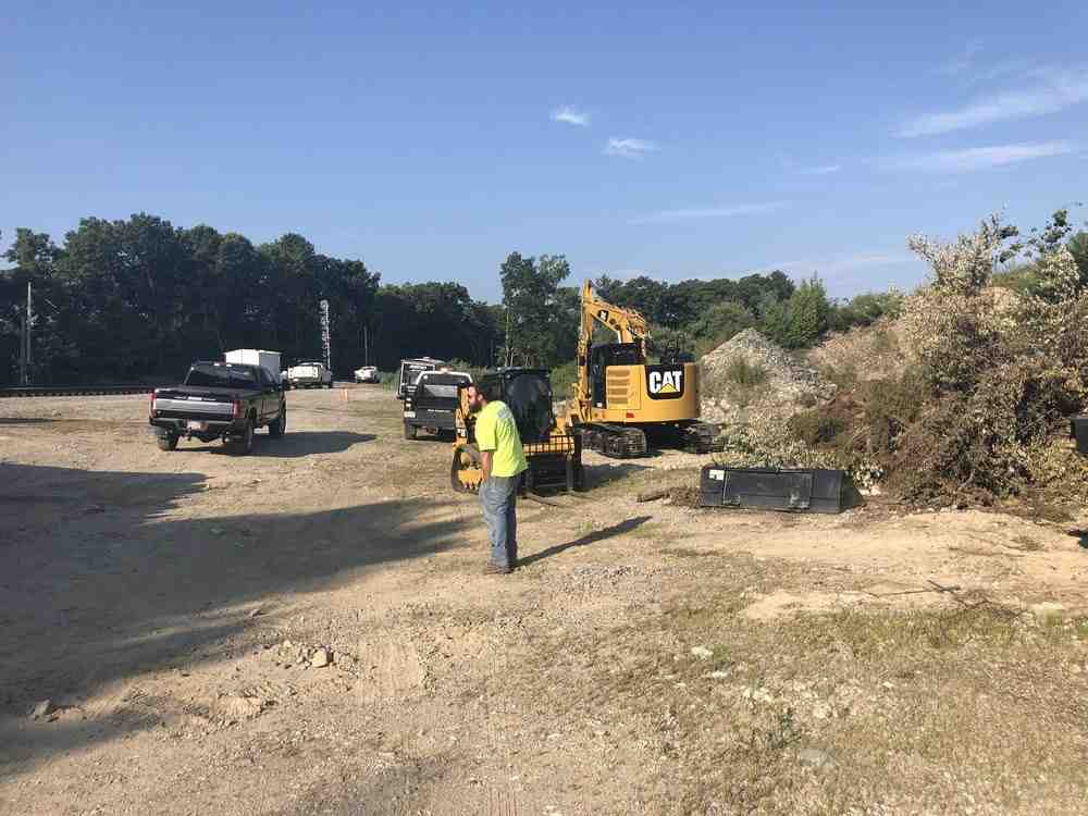Retaining wall construction showing excavated trench, gravel base installation, and first course of stones being placed - Natural stone retaining walls