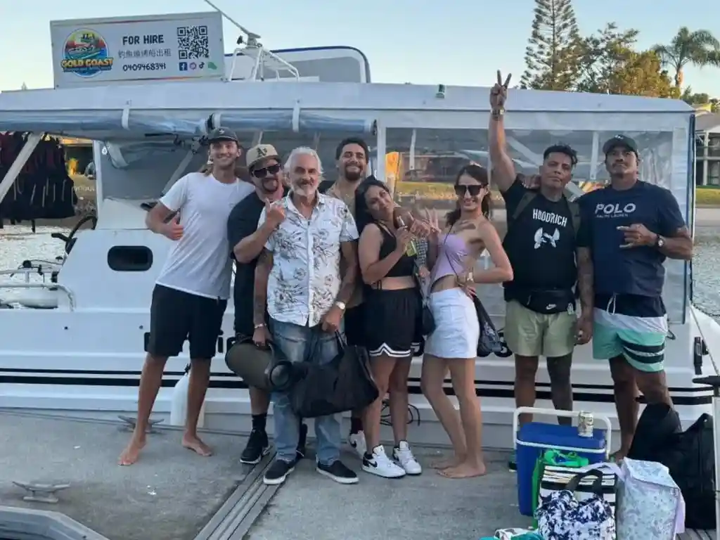 A group of eight mates smiling and posing on a pontoon, showcasing fun boat party ideas on the Gold Coast.
