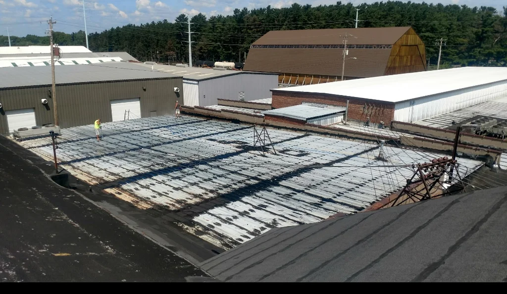 Technician sealing commercial metal roof flashing and fasteners Technician sealing commercial metal roof flashing and fasteners