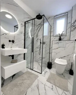A beautifully lit modern small bathroom with a floating vanity, backlit mirror, and large-format wall tiles